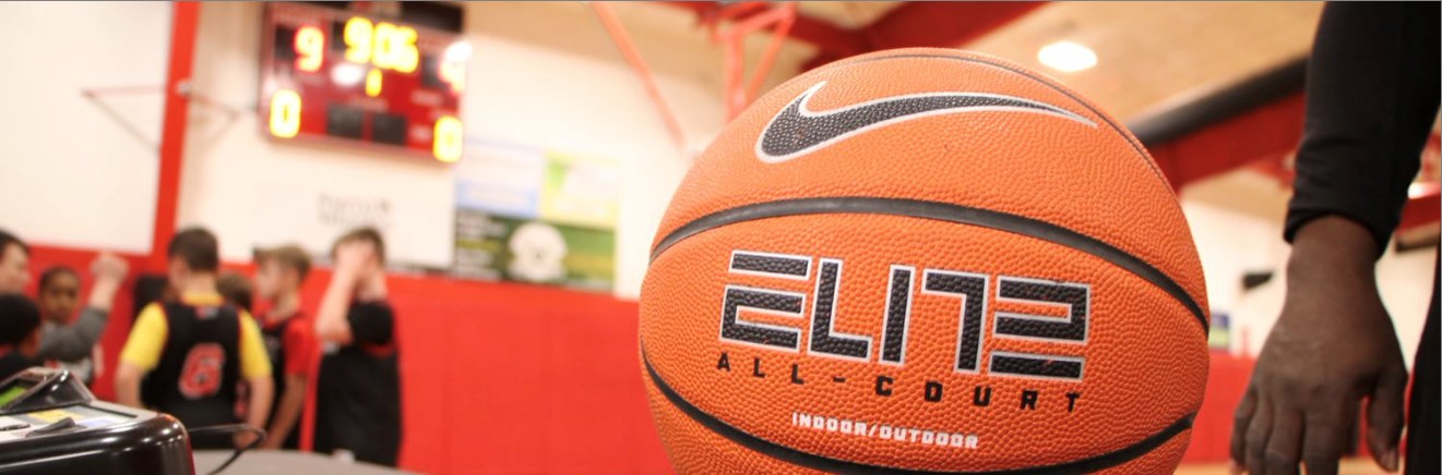 A Nike Elite basketball on the sideline table at an XBL game in Buffalo, with players and a scoreboard behind it
