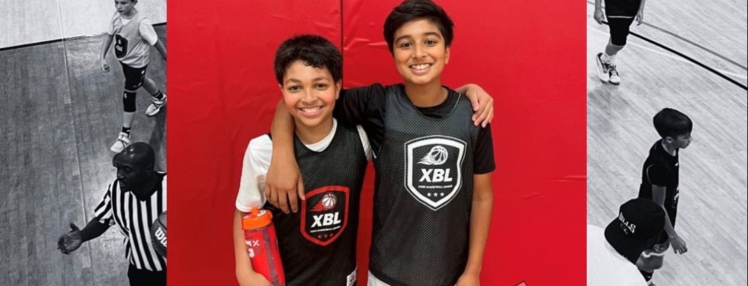 Two smiling young players in XBL pinnies standing arm-in-arm in front of a red gym wall, with black-and-white game action at either side